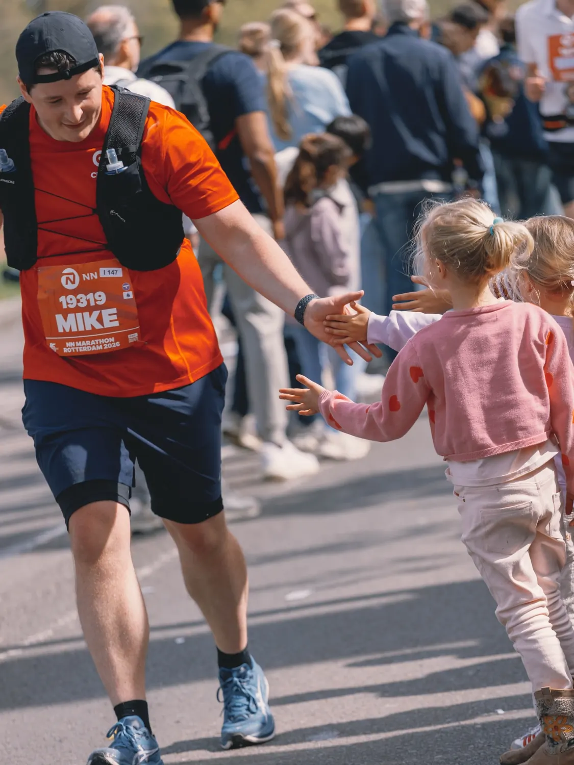 Marathon runner high-fiving children beside the course
